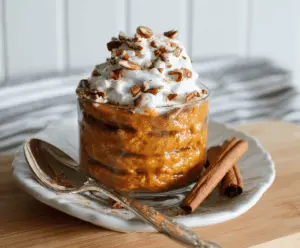 Delicious pumpkin fall breakfast dish featuring creamy pumpkin puree, warm spices, and garnished with toasted nuts and fresh herbs on a rustic plate.