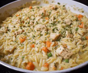 Creamy Chicken Pot Pie Orzo served in a bowl with fresh herbs and flaky pastry crust on top