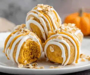 Creamy no-bake pumpkin cheesecake balls garnished with crushed graham crackers and a sprinkle of cinnamon, perfect for fall desserts.