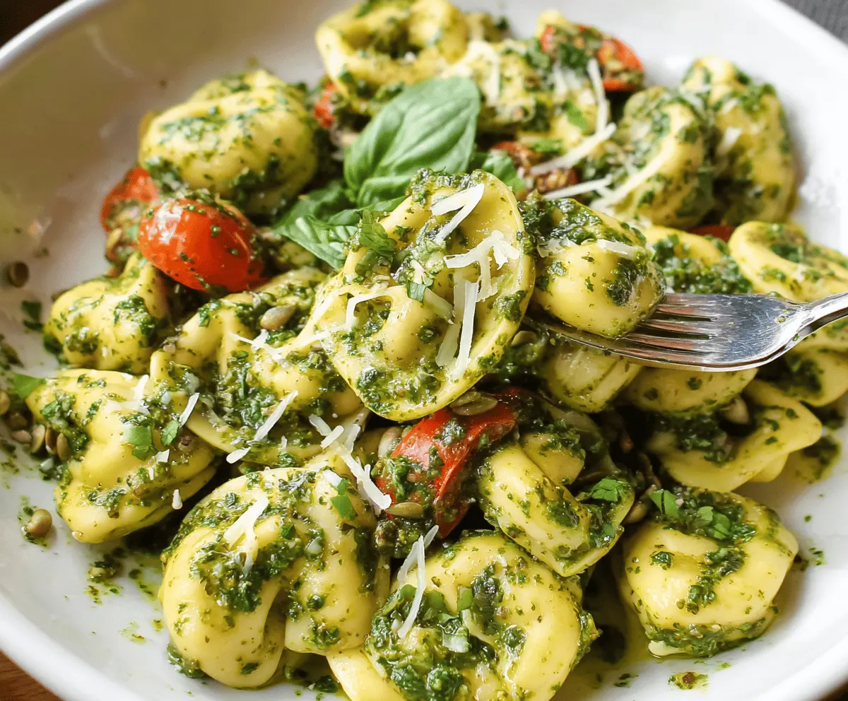 Delicious pesto tortellini pasta dish garnished with fresh basil on a white plate.