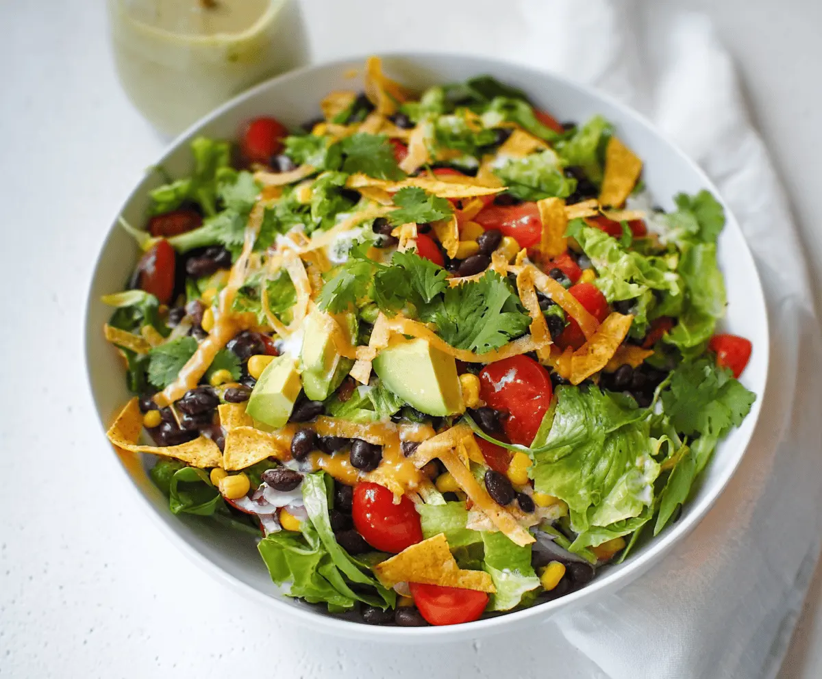 Colorful vegetarian black bean taco salad topped with fresh vegetables, cheese, and lime wedges, perfect for a healthy and delicious meal.