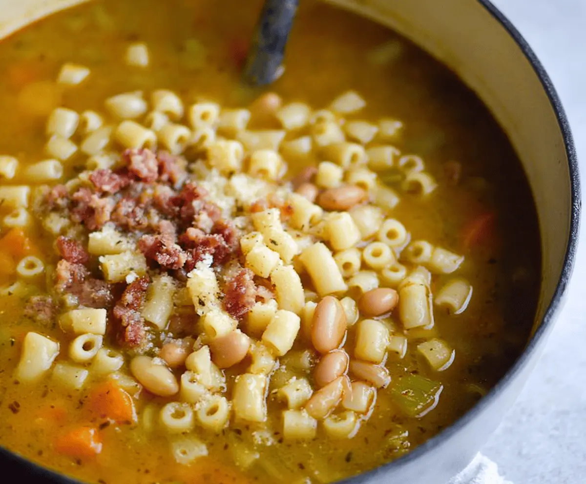 Creamy White Pasta e Fagioli soup in a bowl topped with fresh herbs and grated cheese, served with a slice of crusty bread