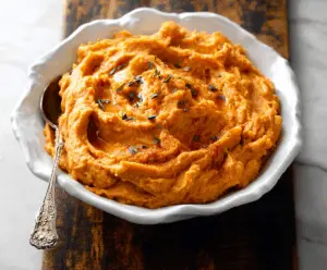 Delicious chipotle mashed sweet potatoes garnished with cilantro and served as a flavorful side dish.