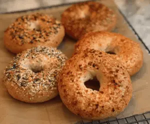 Close-up of freshly baked homemade New York-style bagels on a wooden cutting board.