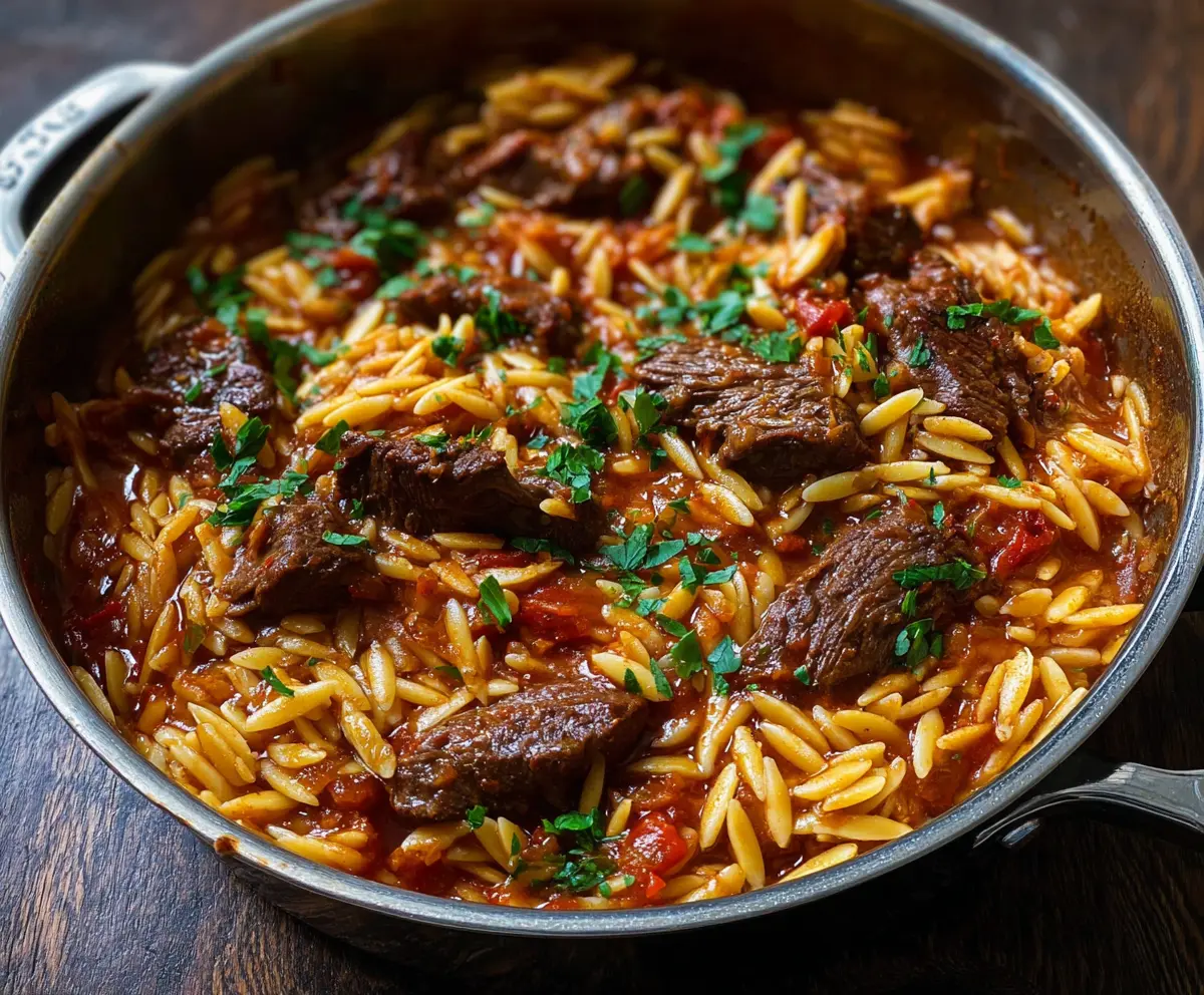 Delicious Beef Giouvetsi with Orzo served in a rustic bowl, showcasing a traditional Greek dish garnished with herbs.