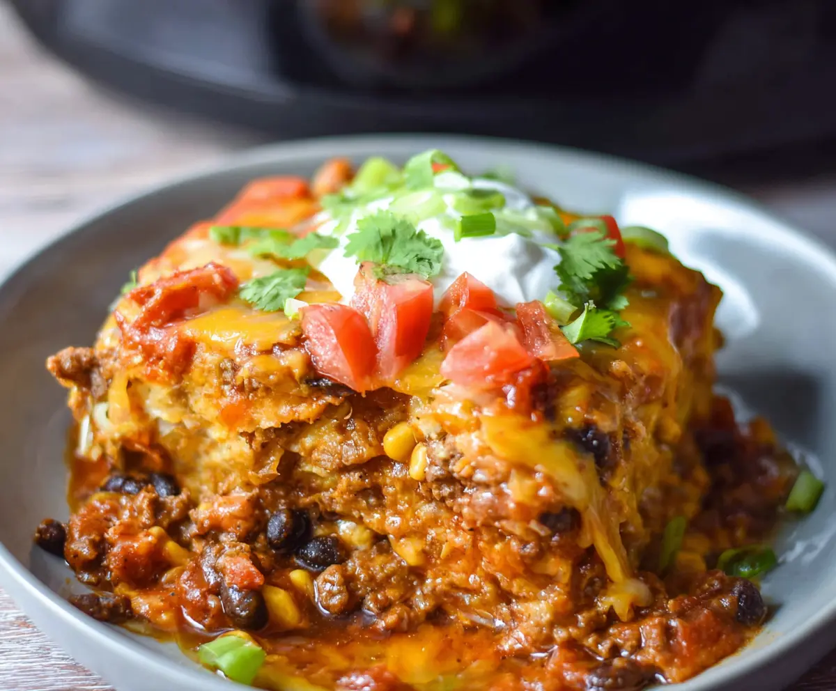 Delicious Crockpot Beef Enchilada Casserole served in a baking dish with melted cheese and garnished with fresh cilantro.