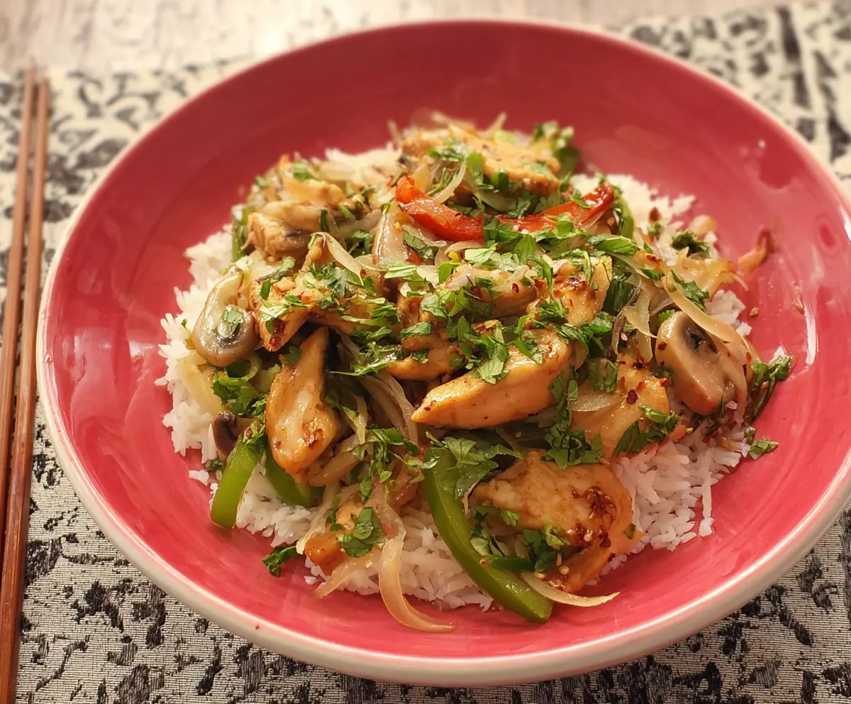Delicious garlic chicken stir fry with fresh vegetables and savory sauce on a cooking plate.