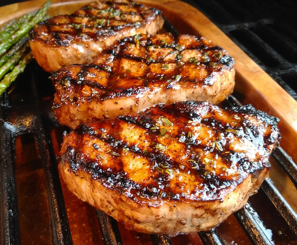Juicy grilled pork loin chops with grill marks on a wooden platter, perfect for a savory summer meal.