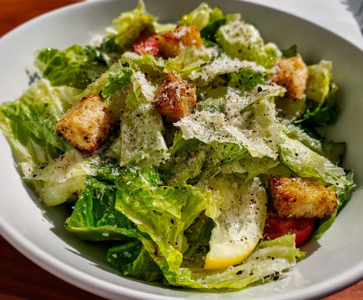 Fresh Nana's Crunchy Lemon Parmesan Salad with lemon slices and grated cheese on a white plate.